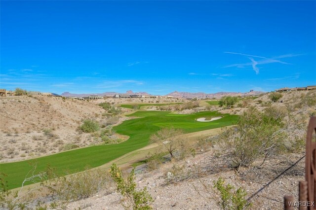 view of community featuring a lawn, golf course view, and a mountain view