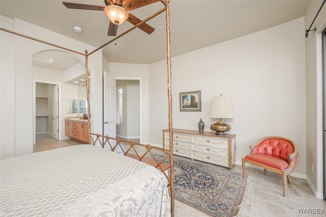 bedroom featuring arched walkways, ceiling fan, baseboards, and ensuite bathroom