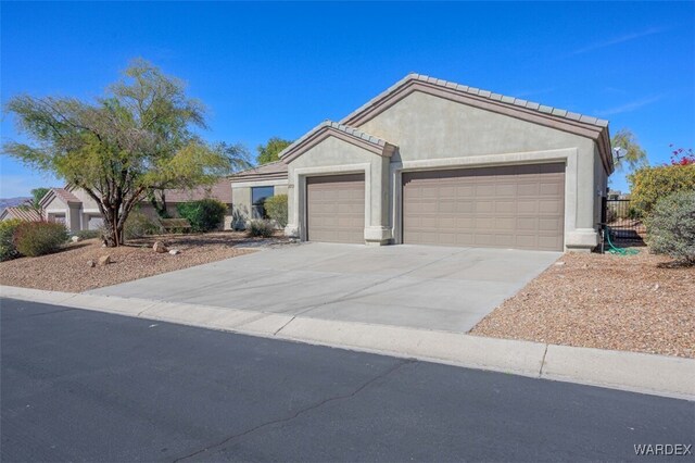 ranch-style house with concrete driveway, a tiled roof, an attached garage, and stucco siding