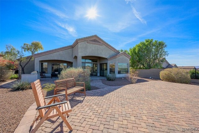 rear view of property featuring fence, a patio, and stucco siding