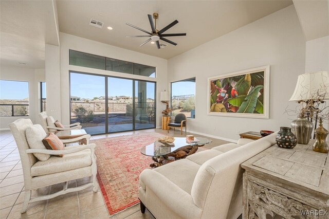 living room featuring light tile patterned flooring, ceiling fan, visible vents, and baseboards