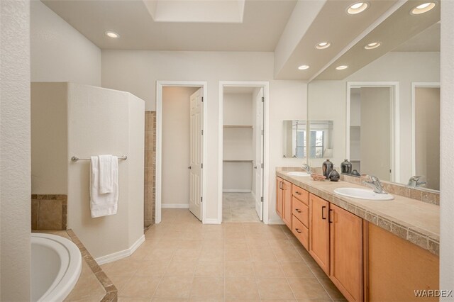 bathroom featuring a relaxing tiled tub, a sink, and recessed lighting