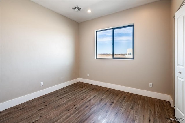 empty room with dark wood-style floors, recessed lighting, visible vents, and baseboards