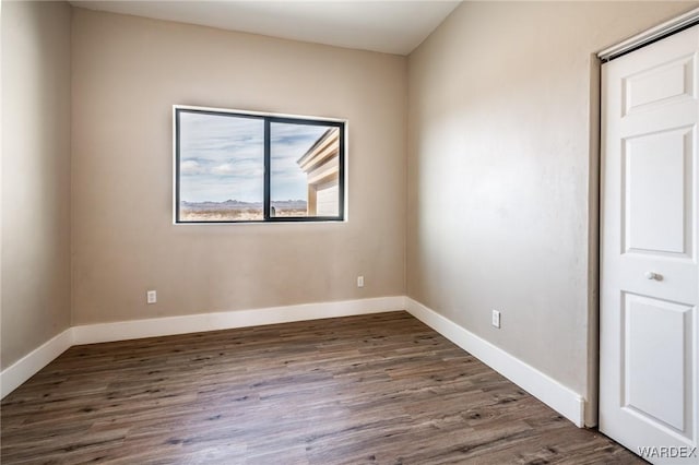 spare room featuring dark wood finished floors and baseboards