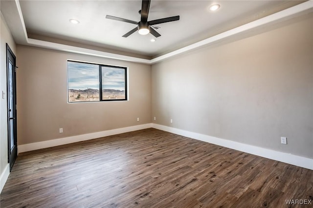 unfurnished room featuring baseboards, ceiling fan, dark wood-type flooring, a tray ceiling, and recessed lighting