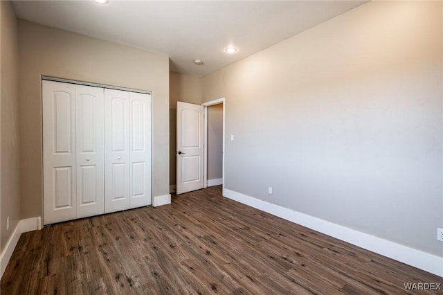 unfurnished bedroom featuring a closet, baseboards, dark wood-type flooring, and recessed lighting