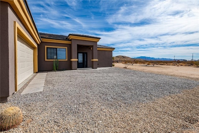 exterior space featuring a garage, a mountain view, and stucco siding