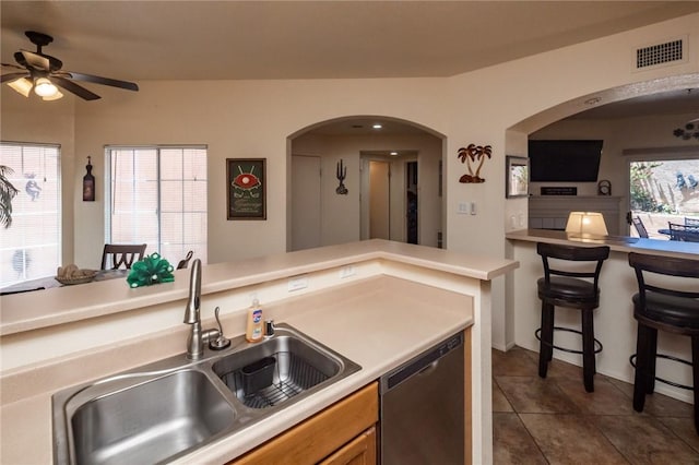 1650 Smoketree Ave Unit 103, Lake Havasu, AZ 86403 - kitchen featuring stainless steel dishwasher, a ceiling fan, arched walkways, dark tile patterned flooring, and light countertops