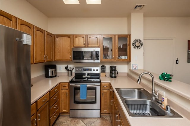 1650 Smoketree Ave Unit 103, Lake Havasu, AZ 86403 - kitchen featuring appliances with stainless steel finishes, brown cabinets, light countertops, and glass insert cabinets
