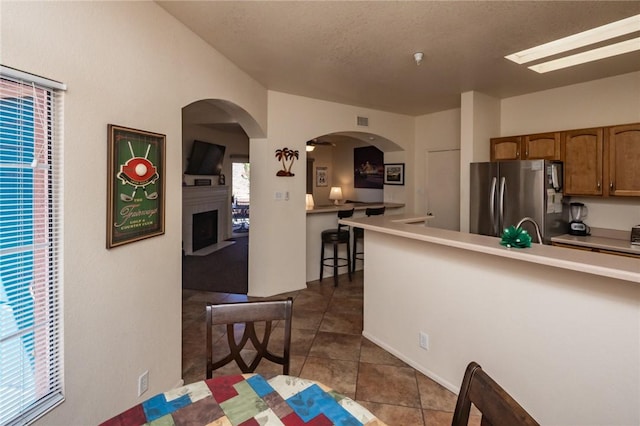 1650 Smoketree Ave Unit 103, Lake Havasu, AZ 86403 - kitchen featuring freestanding refrigerator, a fireplace, dark tile patterned floors, light countertops, and arched walkways