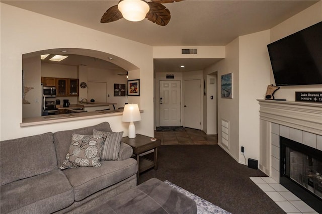 1650 Smoketree Ave Unit 103, Lake Havasu, AZ 86403 - living room with carpet floors, arched walkways, a ceiling fan, and a tile fireplace