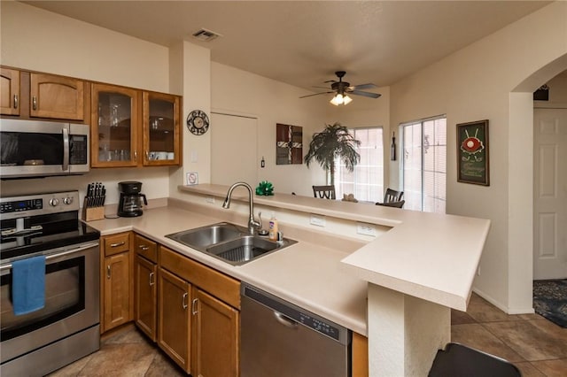 1650 Smoketree Ave Unit 103, Lake Havasu, AZ 86403 - kitchen with stainless steel appliances, a peninsula, brown cabinets, light tile patterned floors, and ceiling fan