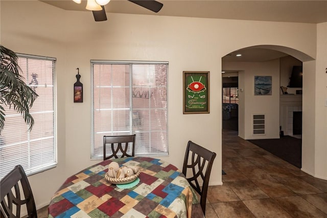 1650 Smoketree Ave Unit 103, Lake Havasu, AZ 86403 - dining room featuring a ceiling fan, arched walkways, a fireplace, and dark tile patterned floors