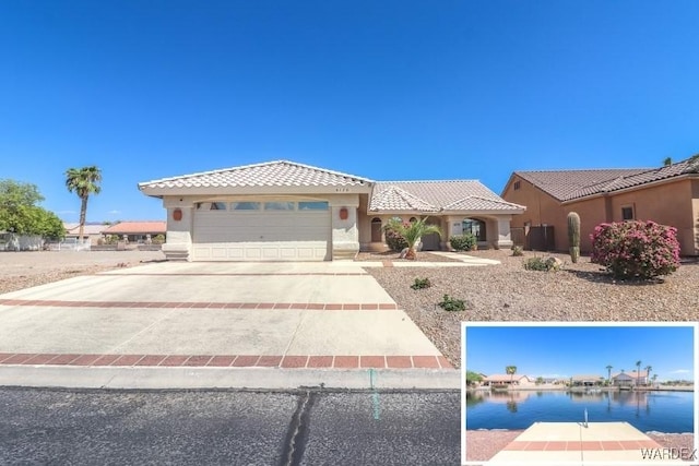 mediterranean / spanish home featuring a tile roof, stucco siding, concrete driveway, a water view, and an attached garage