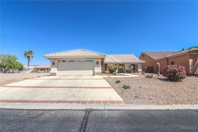 mediterranean / spanish house with a garage, concrete driveway, a tiled roof, and stucco siding