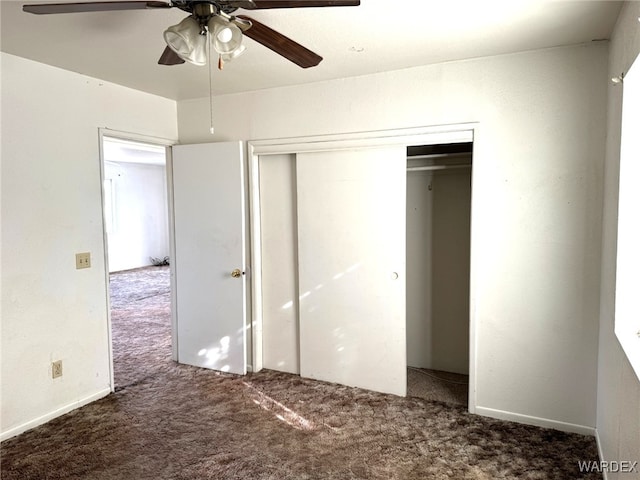 unfurnished bedroom with dark colored carpet, a closet, and a ceiling fan