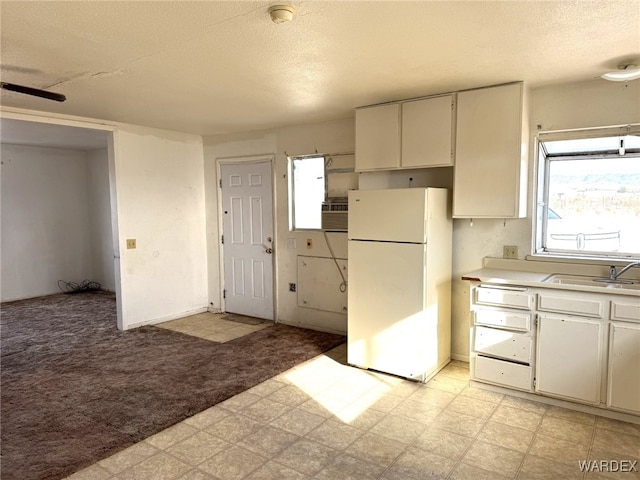 kitchen featuring freestanding refrigerator, light countertops, light floors, and white cabinetry