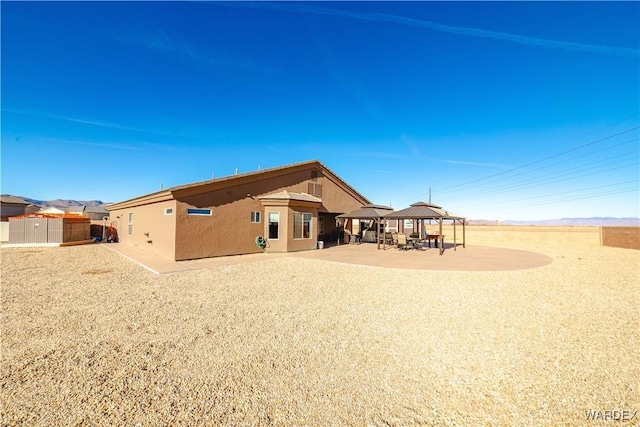 back of property with a gazebo, a patio area, and stucco siding