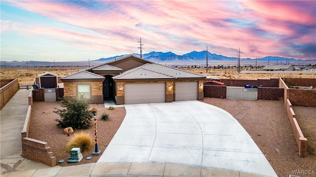 ranch-style house with a garage, driveway, a tiled roof, fence private yard, and a mountain view