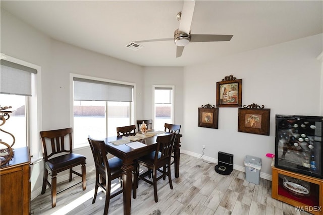 dining space with light wood-type flooring, visible vents, ceiling fan, and baseboards