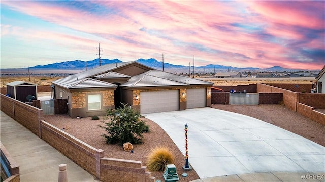 ranch-style home with concrete driveway, a fenced front yard, an attached garage, and a mountain view