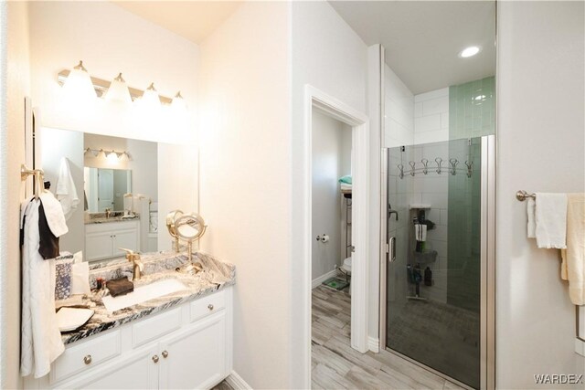 full bathroom featuring baseboards, a shower stall, vanity, and wood finished floors