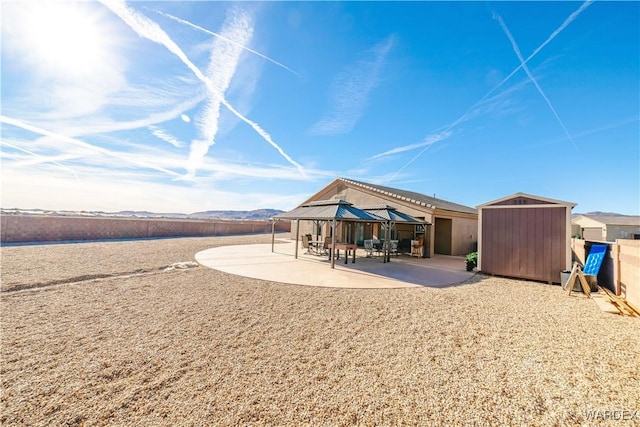 rear view of property featuring a shed, an outbuilding, a patio, and a gazebo