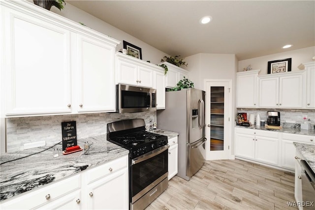 kitchen featuring light stone countertops, recessed lighting, white cabinets, appliances with stainless steel finishes, and decorative backsplash