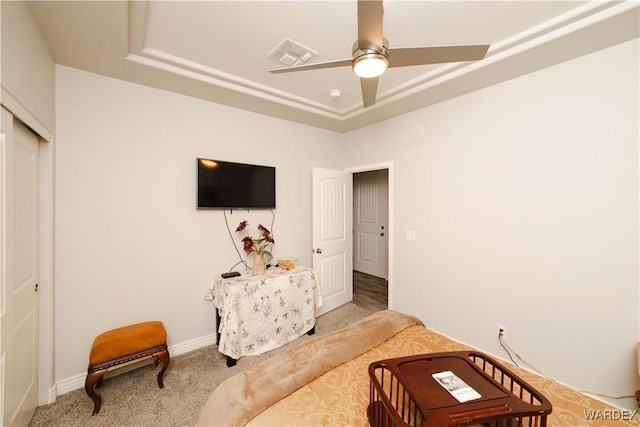 bedroom with visible vents, ceiling fan, a tray ceiling, carpet flooring, and a closet