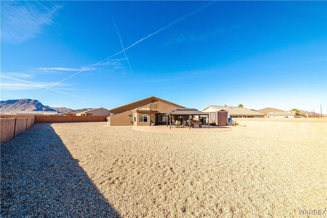 rear view of property with a patio, a fenced backyard, a mountain view, a storage shed, and an outdoor structure