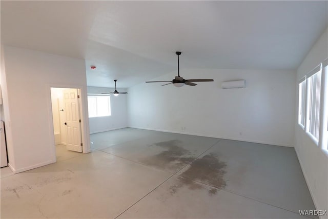 empty room featuring lofted ceiling, concrete floors, a wall mounted air conditioner, and baseboards