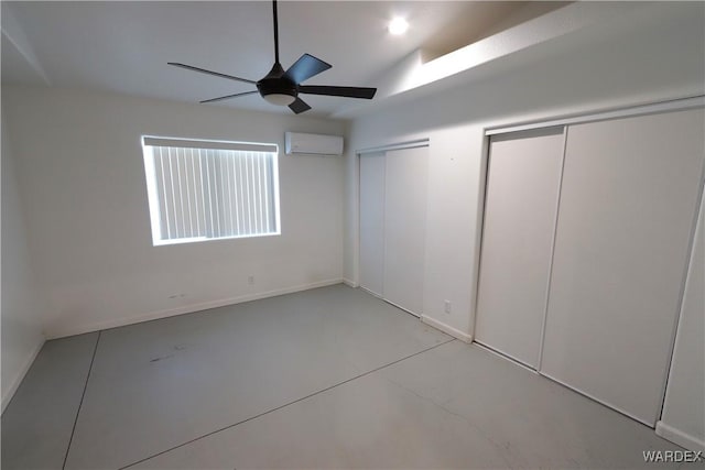 empty room with a ceiling fan, an AC wall unit, concrete floors, and baseboards