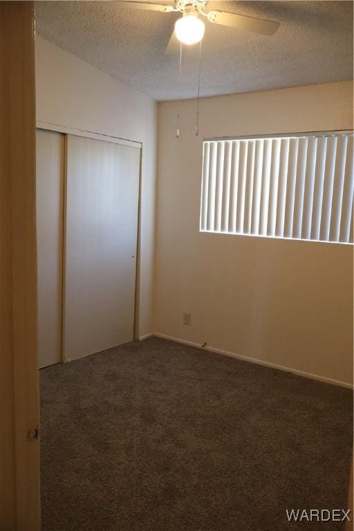 unfurnished bedroom with a textured ceiling, a closet, carpet flooring, and a ceiling fan