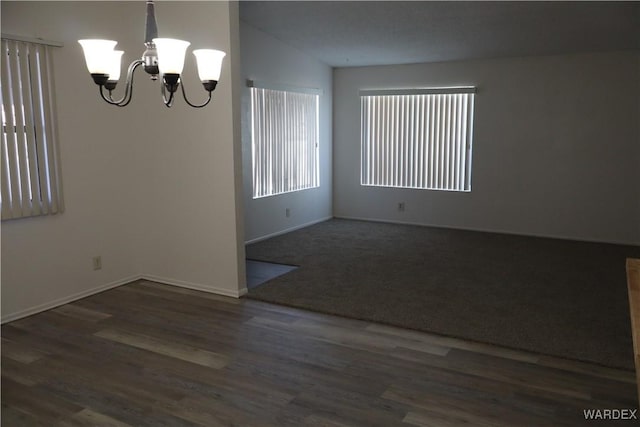 empty room featuring baseboards, dark wood-type flooring, and an inviting chandelier