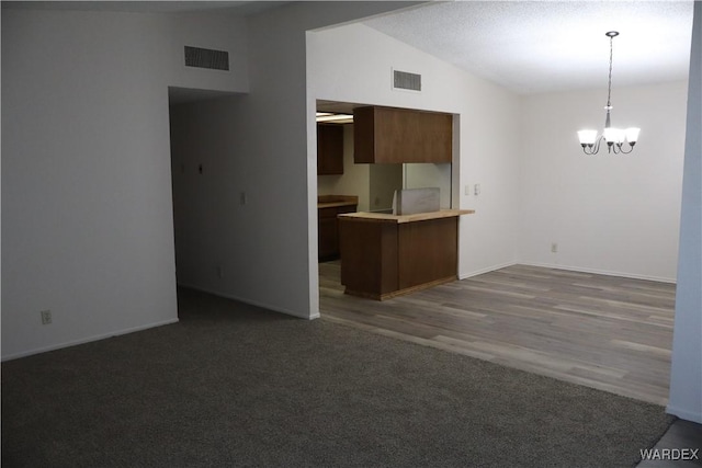 kitchen with lofted ceiling, light countertops, visible vents, and an inviting chandelier