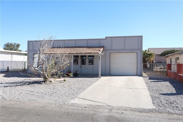 view of front of property featuring an attached garage, fence, and concrete driveway