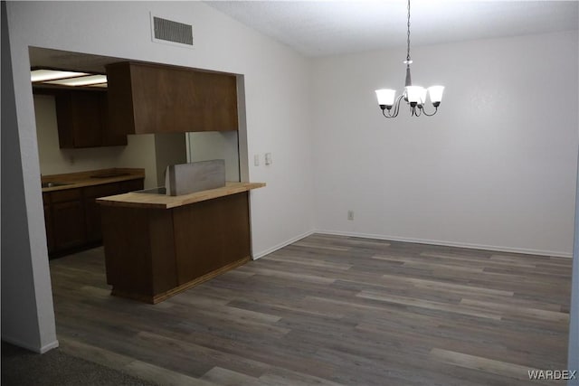 kitchen with a peninsula, visible vents, vaulted ceiling, light countertops, and pendant lighting