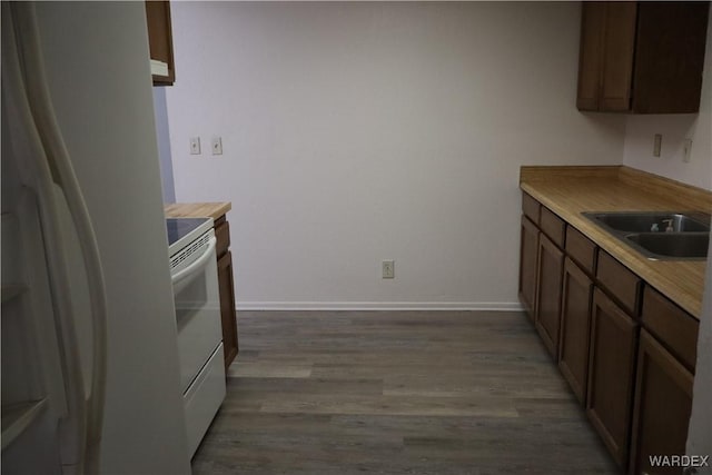 kitchen featuring white appliances, a sink, light wood-style flooring, and baseboards