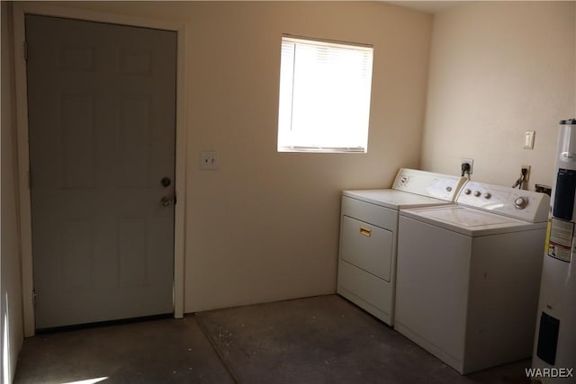 clothes washing area featuring laundry area, water heater, and washer and clothes dryer