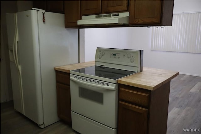 kitchen featuring dark brown cabinetry, under cabinet range hood, white appliances, and dark wood finished floors