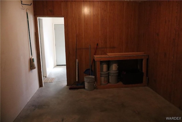 unfurnished living room featuring concrete floors and wooden walls