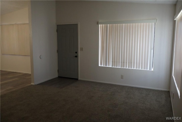 empty room with dark colored carpet and baseboards