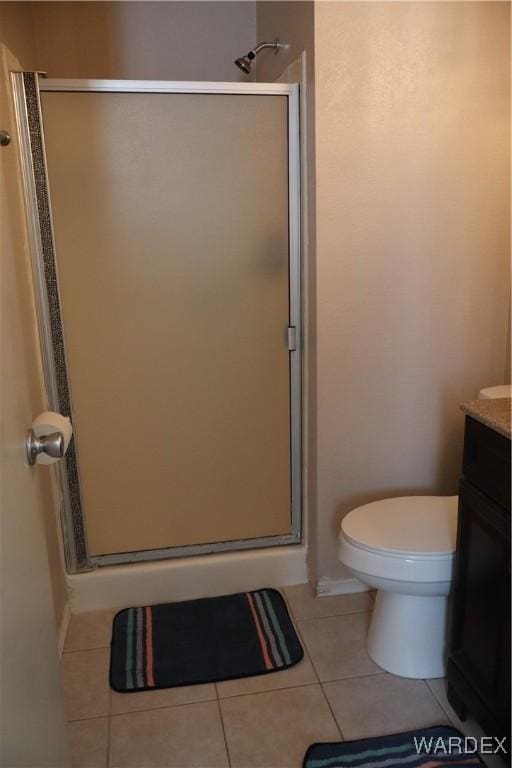 bathroom with toilet, a shower stall, vanity, and tile patterned floors