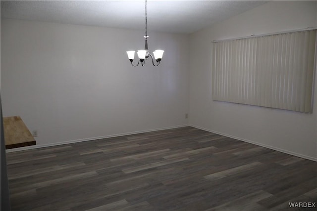 spare room featuring a chandelier, dark wood finished floors, and baseboards