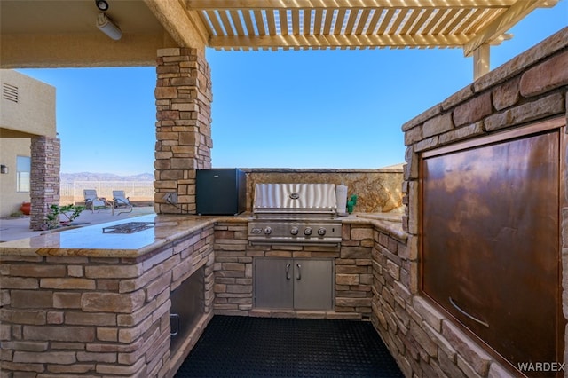 view of patio / terrace with a mountain view, a grill, an outdoor kitchen, and a pergola