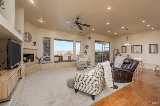 living area with a tiled fireplace, a ceiling fan, and recessed lighting