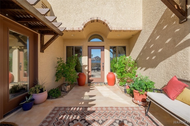 doorway to property featuring a patio area and stucco siding