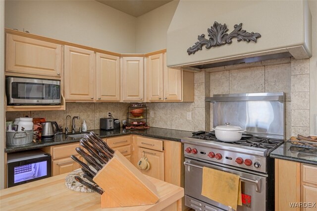 kitchen featuring stainless steel appliances, butcher block counters, a sink, backsplash, and light brown cabinetry