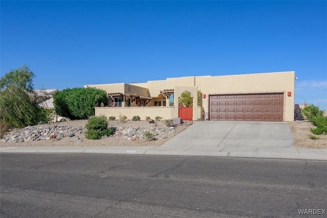 adobe home with driveway, an attached garage, fence, and stucco siding