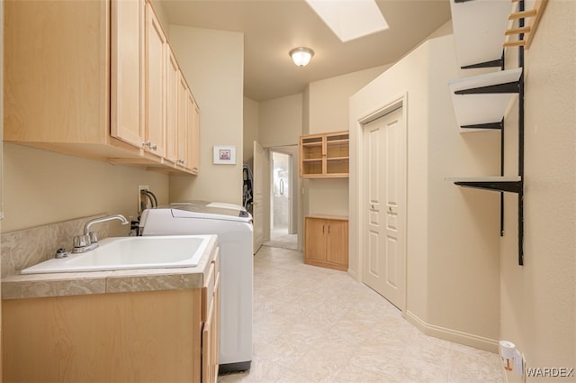 laundry room with a skylight, cabinet space, a sink, independent washer and dryer, and baseboards